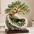 Green natural stone leaf tree with gold-toned branches in a black-and-white bowl-like setting on a dark base