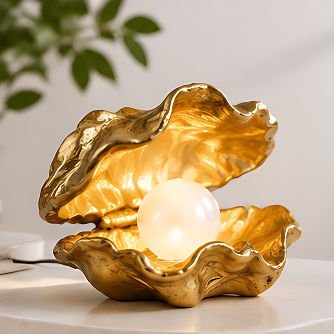 Open gold-toned shell accent lamp with a glowing pearl-shaped orb on a light tabletop