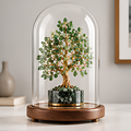 Green stone leaf tree with gold-toned branches under a clear dome on a round solid wood base