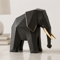 Matte black geometric elephant figurine with gold-toned tusks and ear edging on a light tabletop