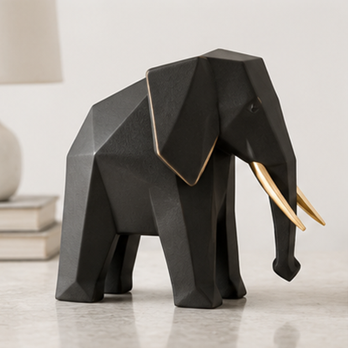 Matte black geometric elephant figurine with gold-toned tusks and ear edging on a light tabletop