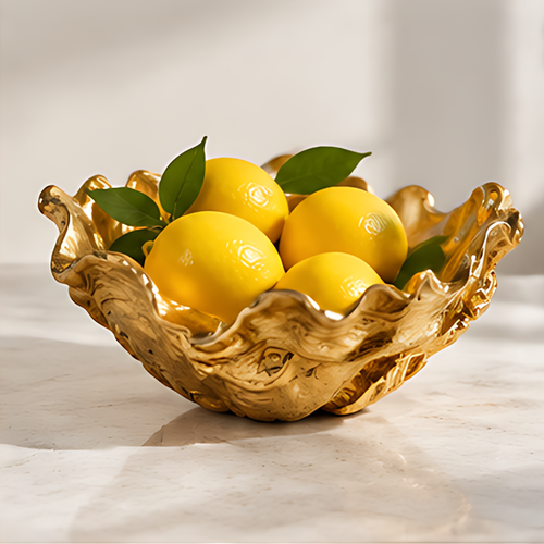 RIVMAROY gold-toned ruffled decorative bowl styled with yellow lemons and green leaves on a light countertop