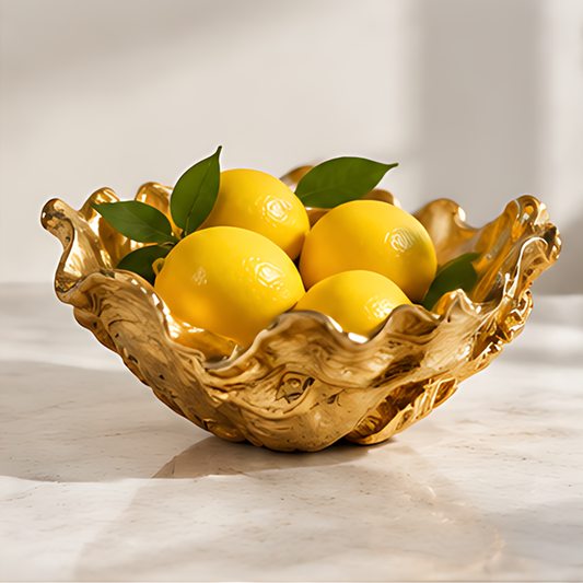 RIVMAROY gold-toned ruffled decorative bowl styled with yellow lemons and green leaves on a light countertop