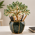 Green leafy tree pen holder with gold-toned trunk and dark green marble-look geometric container, shown with stationery